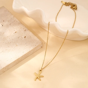 Detailed view of a gold-plated starfish pendant on a fine stainless steel chain