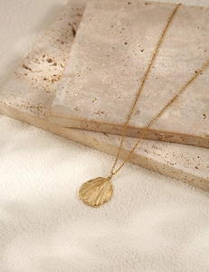 Gros plan du collier doré en acier inoxydable avec pendentif texture nervure de feuille