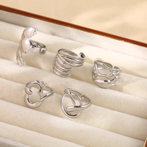 Macro view of five silver-toned irregular adjustable rings on a beige velvet jewelry tray