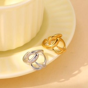 Polished gold and silver crossover leaf rings displayed on elegant ceramic dishware
