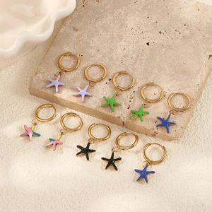 Detailed view of starfish pendant earrings in five vibrant colors on a sandy beach display