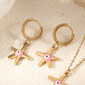 Macro des boucles d'oreilles étoile de mer dorées 14 carats et collier avec émail œil rose
