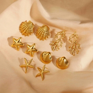 Set orecchini dorati a tema marino con stelle marine e conchiglie su tessuto di seta