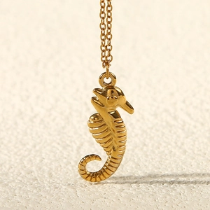 Macro view of a 18k gold seahorse pendant necklace featuring detailed ridges on a fine chain