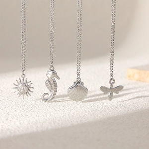 Silver-tone necklace set featuring sun, seahorse, shell, and bee pendants on a fine chain