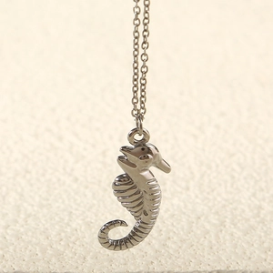 Close-up of a silver seahorse pendant with textured details on a thin chain link
