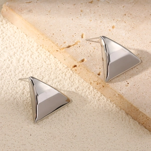 Close-up of geometric triangle silver earrings on a minimalist stone background