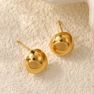 Macro detail of polished 18k gold plated stainless steel stud earrings on stone texture