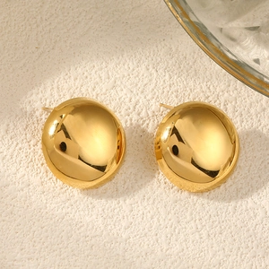 Close-up of golden minimalist round stud earrings with a high-polished mirror finish