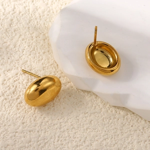 Macro view of gold teardrop earrings showing mirror polished surface and metal posts