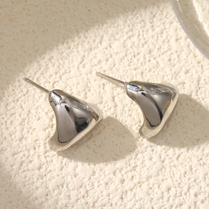 Macro shot of silver-colored teardrop stud earrings with a polished mirror finish on stone