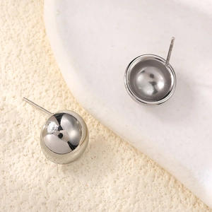 Macro view of polished silver steel sphere stud earrings with smooth mirror finish