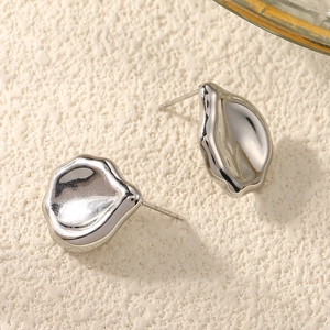 Detailed view of silver heart earrings with liquid metal texture on white background
