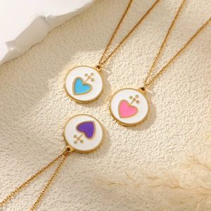 Trois colliers avec pendentifs cœurs rose, bleu et violet sur fond texturé de style luxueux