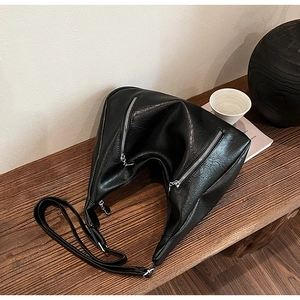 Detail of black pebbled PU leather tote with dual silver zippers and adjustable strap