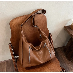 Detail of vintage brown hobo bag featuring dual silver zippers and textured faux leather