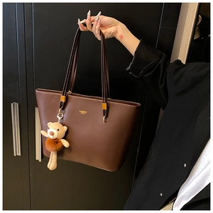 Detail of dark brown tote bag with smooth leather finish and cute bear keychain