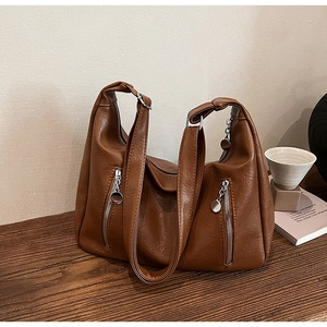 Close-up of brown vintage tote bag with silver zippers on a wooden table setup