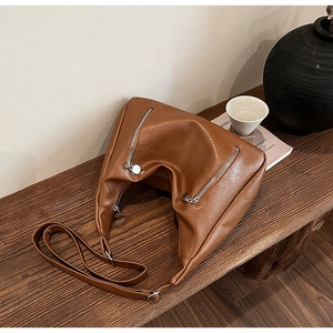 Detail of vintage brown PU leather tote with silver zippers on a wooden bench
