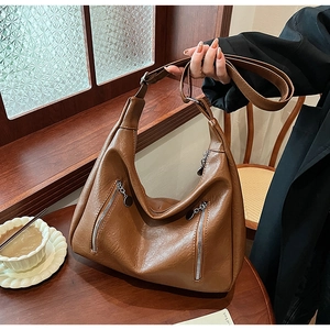 Close-up of caramel brown pebble leather tote bag with stylish zipper details in cafe