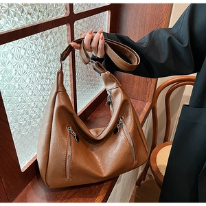 Detail view of caramel brown retro tote bag with dual silver zippers and leather texture