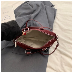 Internal view of burgundy suede handbag with beige lining and silver zipper closure