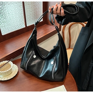 Detail of vintage black tote bag with dual zippers and litchi texture in a cafe setting