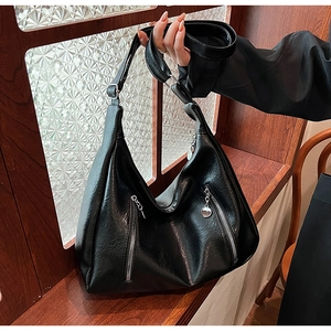 Detail of black pebbled leather Hobo bag with parallel silver zippers and adjustable strap