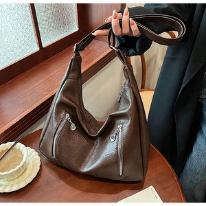 Detail of vintage dark brown faux leather tote with silver zippers and wide shoulder strap