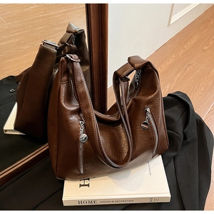 Detail of dark brown tote bag showing its pebbled leather texture and metal zipper
