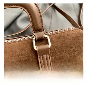 Close-up of premium brown suede bag featuring silver hardware and precise stitching details