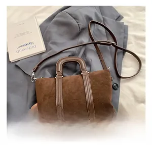 Detailed close-up of dark brown suede boston bag texture on stylish office suit