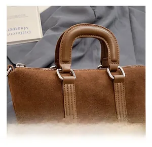 Detail of brown suede handbag featuring vintage leather handle and silver metal hardware