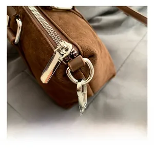 Detailed close-up of premium brown suede texture with silver metal hook and zipper
