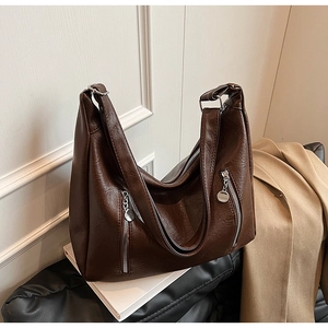 Close-up of dark brown leather hobo bag featuring side zippers and polished metal hardware