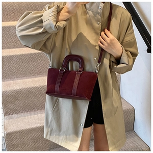 Detail of burgundy frosted suede bag showing textured finish and leather handle craftsmanship