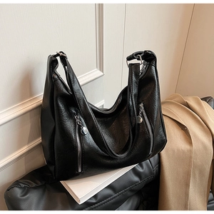 Detail of black faux leather tote with textured finish and silver vertical zippers