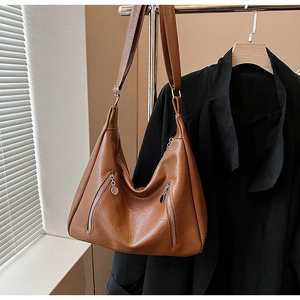 Close-up of caramel leather tote bag with lychee texture and silver zipper details