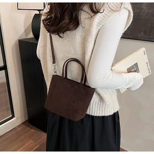 Sac seau en daim marron porté par un mannequin pour un look décontracté chic