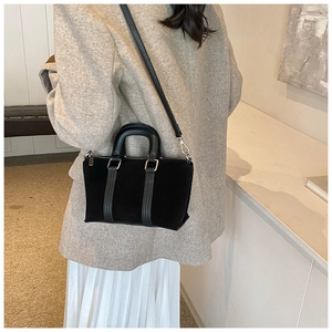 Lifestyle view of a black frosted leather satchel with silver hardware and shoulder strap