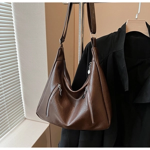 Detail of dark brown vintage tote bag with glossy pleated leather and silver zippers
