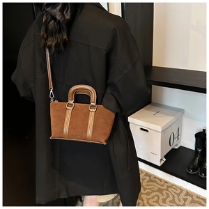 Brown frosted suede crossbody bag shown on model in a minimalist interior setting