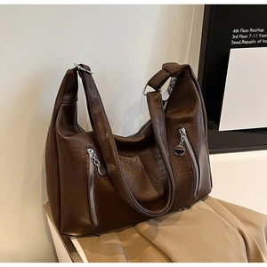 Close-up of dark brown lychee pattern leather tote bag with silver metal ring and zippers
