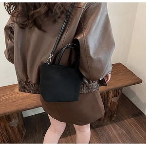 Petit sac fourre-tout noir minimaliste avec bandoulière et détails argentés sur modèle