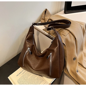 Detail of dark brown retro hobo bag with oil wax leather texture and front zipper pockets