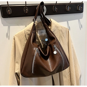 Detail of dark brown large tote bag with silver zippers and soft leather texture