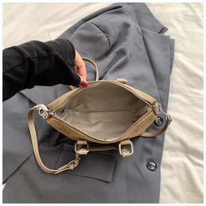 Detail view of khaki matte leather crossbody bag showing wide zipper opening and lining