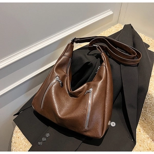 Detail view of vintage brown leather tote bag with silver zippers on a black blazer
