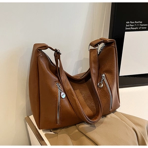 Detailed macro view of the brown leather tote bag with silver dual zipper hardware