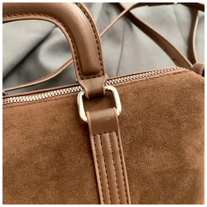 Close-up of brown frosted suede texture and silver metal hardware on a vintage handbag
